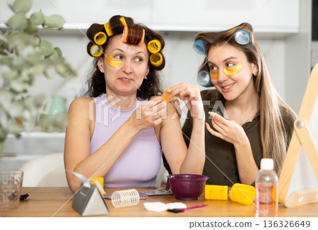 Female friends in curlers using under-eye patches during self-care routine Female friends in curlers using under-eye patches during self-care routine 136326649