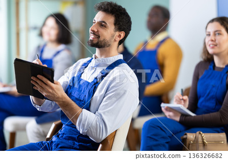 Young man worker listening to lecture and taking notes on tablet Young man worker listening to lecture and taking notes on tablet 136326682