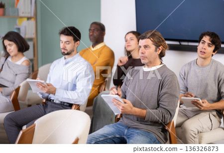 Adult man listens and takes notes in lecture hall 136326873
