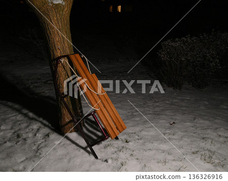 wooden sled by a tree in the snow at night 136326916