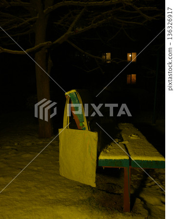 tote bag hanging on the back of a snowy bench at night in the park tote bag hanging on the back of a snowy bench at night in the park 136326917