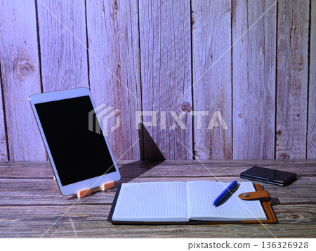 white tablet on a stand next to an open notebook and a blue pen white tablet on a stand next to an open notebook and a blue pen 136326928