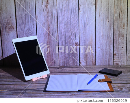 tablet in a white frame on a stand with a notebook on a wooden surface tablet in a white frame on a stand with a notebook on a wooden surface 136326929