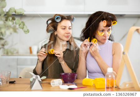 Two women curling their hair with curlers Two women curling their hair with curlers 136326967