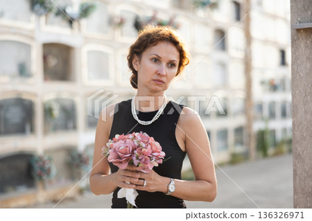 Woman brought flowers to the cemetery and cries over the death of beloved relative 136326971