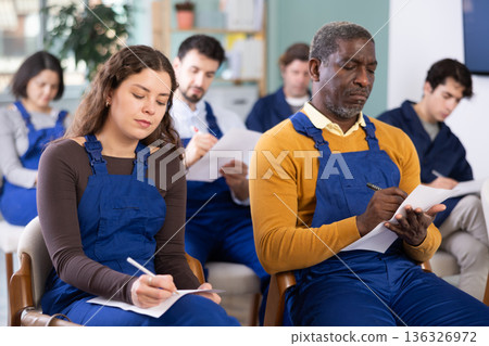 Multinational group workers listens and takes notes lectures in lecture hall Multinational group workers listens and takes notes lectures in lecture hall 136326972