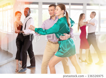 Couples dancing tango, enjoying dance moves in dance salon Couples dancing tango, enjoying dance moves in dance salon 136326975