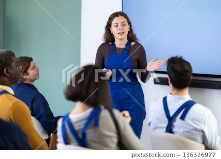 Young woman worker gives lecture in auditorium Young woman worker gives lecture in auditorium 136326977
