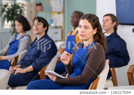 Young woman worker listens and takes notes in lecture hall Young woman worker listens and takes notes in lecture hall 136327094
