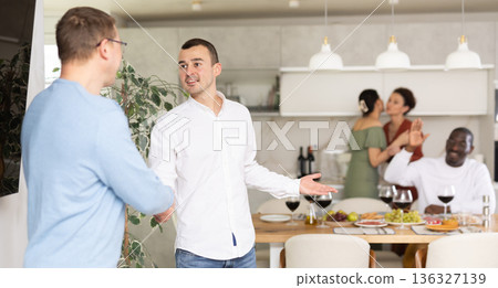 Warm handshake from host to friend at home dinner event Warm handshake from host to friend at home dinner event 136327139