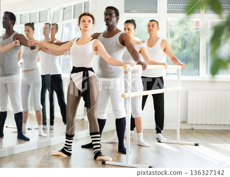 Ballet rehearsal in dance studio - men and women stand in second position near ballet barre 136327142