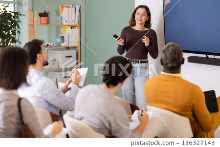 Female teacher giving lesson for students in classroom. Speaks into microphone Female teacher giving lesson for students in classroom. Speaks into microphone 136327143