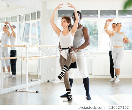 Confident ballet dancer supporting female partner in lifts Confident ballet dancer supporting female partner in lifts 136327162