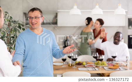 Happy middle-aged man welcoming his guest at home Happy middle-aged man welcoming his guest at home 136327172