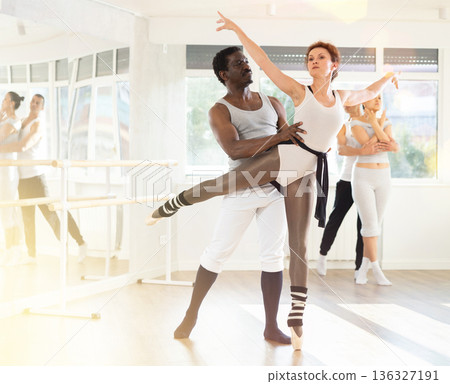 Couple of ballet dancers showcasing skillful supports during group rehearsal Couple of ballet dancers showcasing skillful supports during group rehearsal 136327191