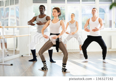 Female ballet dancer performing dance moves at group rehearsal Female ballet dancer performing dance moves at group rehearsal 136327192
