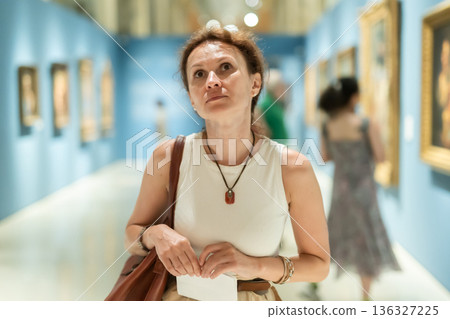 Woman viewing art gallery with brochure 136327225