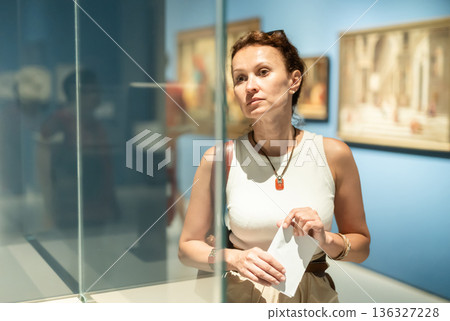 Woman looks at hall of paintings and sculptures 136327228