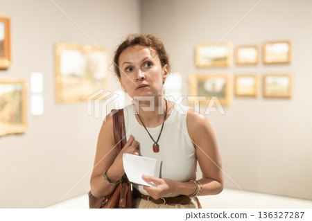 Young female visitor looking at exhibition in museum of ancient art Young female visitor looking at exhibition in museum of ancient art 136327287
