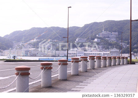 從長崎港濱海大道眺望巨大的造船廠起重機和沿著山坡延伸的城市景觀。 136329357
