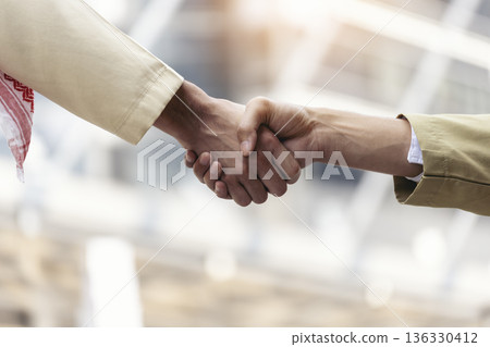 Arab Businessman shaking hands together. Teamwork business partner wear Muslim dress Shake Hands with Partnership Concept. Success UAE diversity people trust make commitment by handshake 136330412