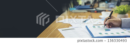 Asian Female freelance using laptop at home office desk. Woman reading financial graph chart Planning analyzing marketing data. Asian female people working office firm with business stuff, coffee cup 136330493