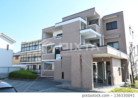 A modern, low-rise apartment building with tiled walls that stands out against the blue sky 136330841