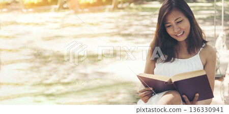 Banner woman holding book reading magazine at green park natural garden. Young woman relaxation read open book self study. Happiness University women smiling. Women sit in green park with copy space 136330941