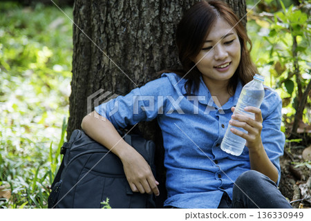 Young Woman Drinking Water bottle outdoor park traveler. Asian female drinking water bottle healthy person happy smile. Happiness Beautiful asian chinese women holding mineral water bottle lifestyle Young Woman Drinking Water bottle outdoor park traveler. Asian female drinking water bottle healthy person happy smile. Happiness Beautiful asian chinese women holding mineral water bottle lifestyle 136330949