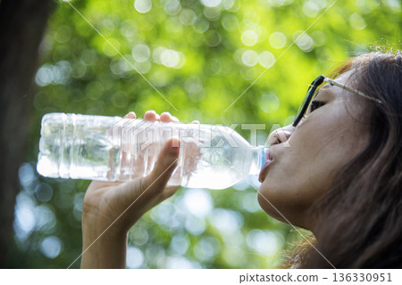 Young Woman Drinking Water bottle outdoor park traveler. Asian female drinking water bottle healthy person happy smile. Happiness Beautiful asian chinese women holding mineral water bottle lifestyle 136330951