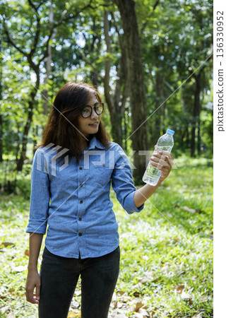 Vertical Young Woman Drinking Water bottle outdoor park traveler. Asian female drinking water bottle healthy happy person. Vertical images Beautiful asian women holding mineral drink bottle lifestyle Vertical Young Woman Drinking Water bottle outdoor park traveler. Asian female drinking water bottle healthy happy person. Vertical images Beautiful asian women holding mineral drink bottle lifestyle 136330952