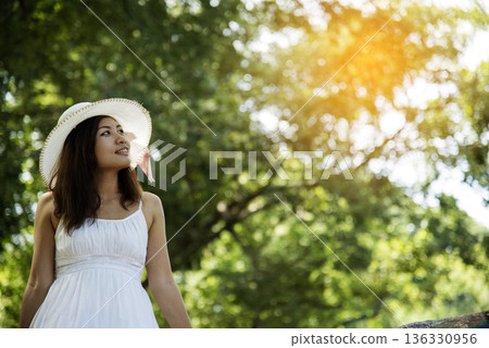Portrait Asian Woman relaxing in green park. Happy Relax asian woman smiling face at outdoors garden. Young women enjoy nature freedom lifestyle. Greenery wellbeing outside beauty in nature. 136330956