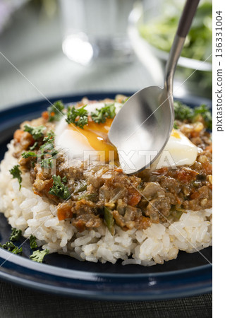 餐桌上，我用湯匙舀起一份配有半熟蛋的肉末咖哩。 136331004