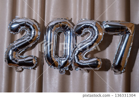 Happy new year 2027 metallic balloons on atlas textile background. Greeting card silver foil balloons numbers Christmas holiday concept. Celebration party congratulation Happy new year 2027 metallic balloons on atlas textile background. Greeting card silver foil balloons numbers Christmas holiday concept. Celebration party congratulation 136331304