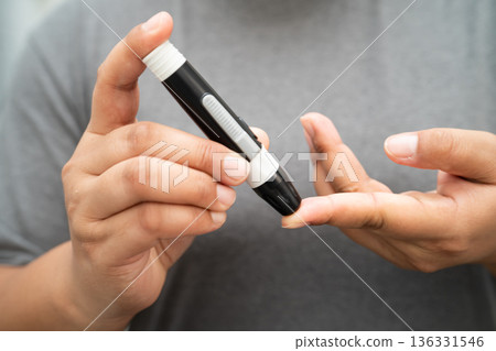 Asian woman self testing to check blood sugar level diabetes by digital lancet on finger at home. 136331546