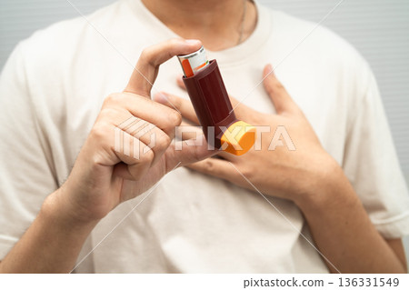 Asthma and chronic obstructive pulmonary disease COPD, Asian young man using metered dose inhaler MDI. Asthma and chronic obstructive pulmonary disease COPD, Asian young man using metered dose inhaler MDI. 136331549