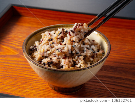 Picking up a bowl of mixed grain rice placed on a wooden tray with chopsticks Picking up a bowl of mixed grain rice placed on a wooden tray with chopsticks 136332761