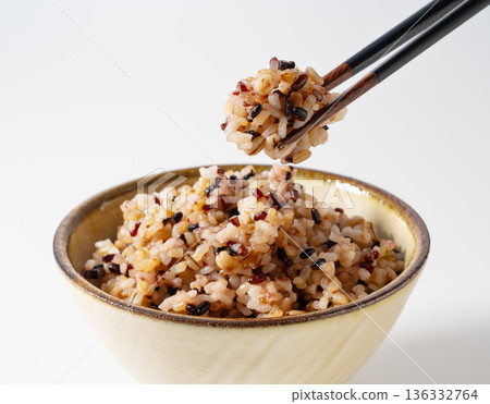 Mixed grain rice served in a bowl on a white background and picked up with chopsticks 136332764