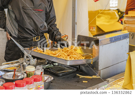 炸薯條在油炸鍋裡炸製;食品攤位上的烹飪場景;店員的烹飪過程 炸薯條在油炸鍋裡炸製;食品攤位上的烹飪場景;店員的烹飪過程 136332862