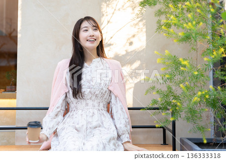 在咖啡館露台上放鬆的年輕女子 136333318