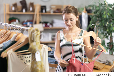 Young woman choosing jumpsuit in clothing store 136333610