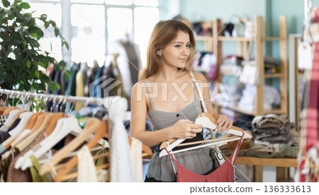 Young girl choosing summer dress in clothing store Young girl choosing summer dress in clothing store 136333613