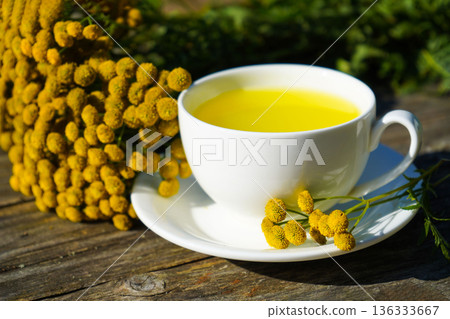 Healthy tansy tea in white cup and tansy flowers. Tansy infusion or decoction has choleretic and antispasmodic effect. 136333667