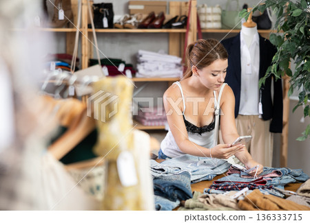Young woman checking the quality of jeans using a steamer QR code on label Young woman checking the quality of jeans using a steamer QR code on label 136333715