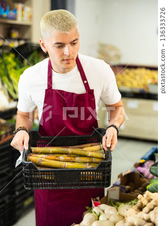 Supermarket employee carries box of asparagus Supermarket employee carries box of asparagus 136333726