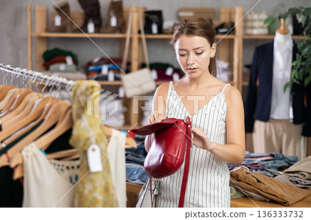 Near rack, girl buys lady handbag, chooses items Near rack, girl buys lady handbag, chooses items 136333732