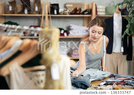 Young woman choosing jeans in clothing store 136333747
