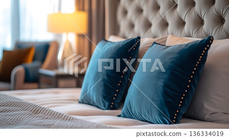 The bed is made with two blue pillows and a white pillow The bed is made with two blue pillows and a white pillow 136334019