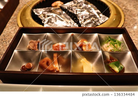 一家烤肉餐廳的開胃菜拼盤和桌面烤爐，提供各種食材 136334484