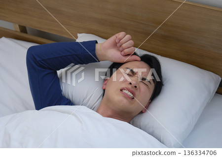 Man in his 20s sleeping in bed with fever Man in his 20s sleeping in bed with fever 136334706